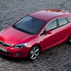 Czerwona Astra J na bruku. Czy Opel Astra J to dobry samochód? Ten model z pewnością wygląda stylowo i zachęca do jazdy.