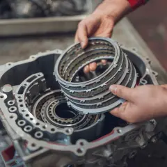 Mechanik trzyma stos tarczek sprzęgłowych do skrzyni biegów.
