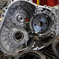 Wnętrze skrzyni biegów z widocznym wybierakiem zmiany biegów, kołami zębatymi i innymi elementami mechanicznymi.