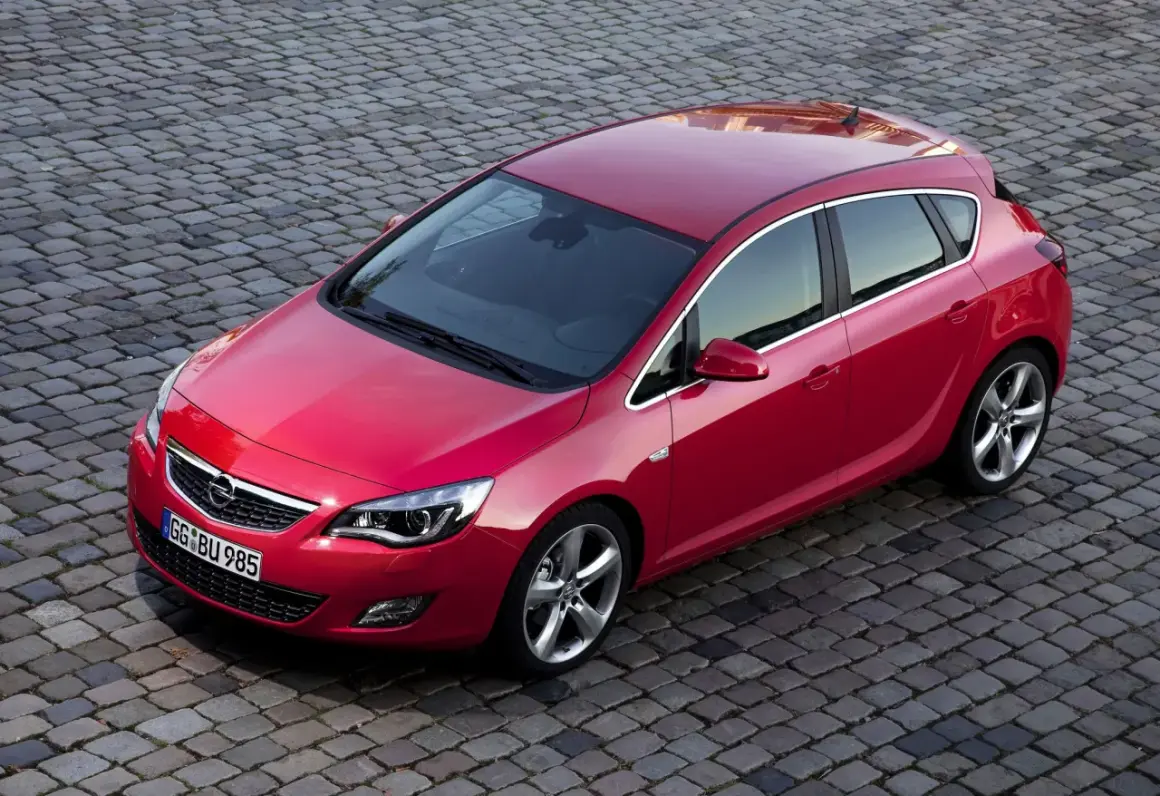 Czerwona Astra J na bruku. Czy Opel Astra J to dobry samochód? Ten model z pewnością wygląda stylowo i zachęca do jazdy.