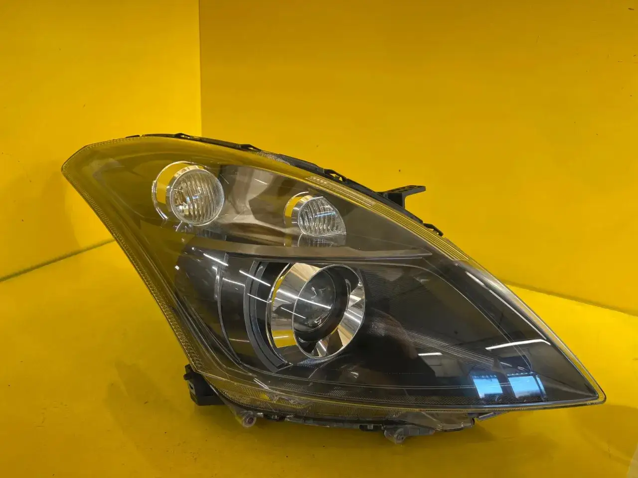 Reflektor do Suzuki Swift, z czarnym wnętrzem i chromowanymi detalami, gotowy do montażu.