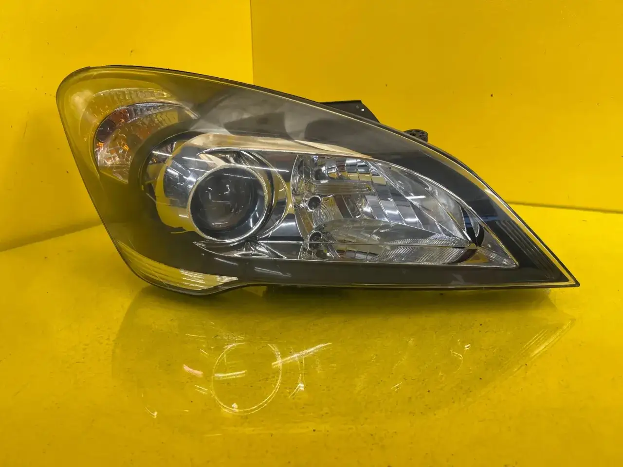 Reflektor przedni do Kia Ceed, z widocznym odbłyśnikiem i pomarańczowym kierunkowskazem.