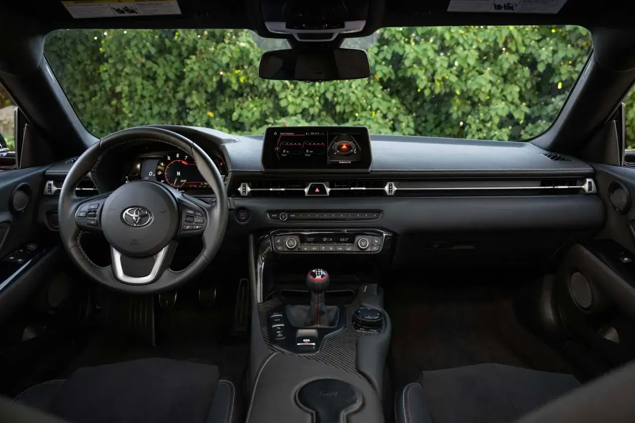 Wnętrze nowej Toyoty Supry: kierownica, cyfrowy kokpit, ekran multimediów i dźwignia zmiany biegów.